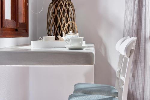 un mostrador blanco con dos tazas y una silla en Mirabeli Apartments & Suites, en Pollonia