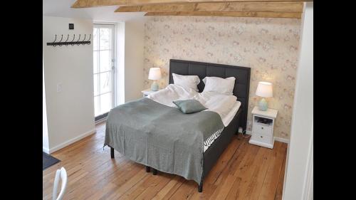 a bedroom with a large bed and two lamps at Enø Bageri's Hotelværelser in Karrebæksminde