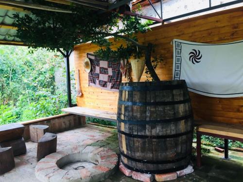 a wooden cabin with a barrel and a tree at Lazuri Keria Family Guesthouse in Khoni