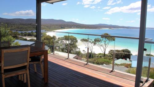 a balcony with a desk and a view of the ocean at SEA EAGLE COTTAGE Amazing views of Bay of Fires in Binalong Bay