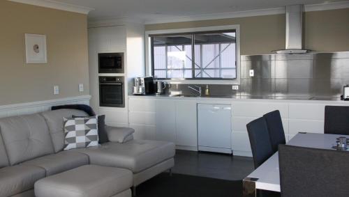 a living room with a couch and a kitchen at SEA EAGLE COTTAGE Amazing views of Bay of Fires in Binalong Bay