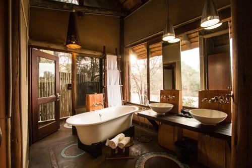 uma casa de banho com 2 lavatórios e uma banheira em Rhino Post Safari Lodge em Skukuza