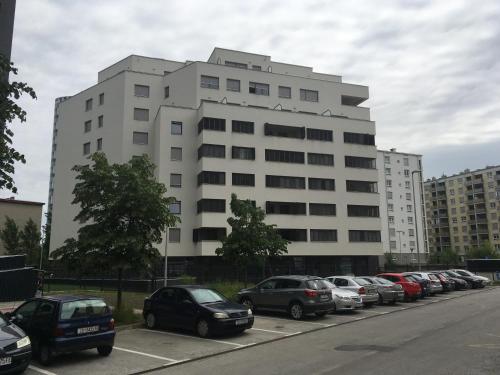 a large white building with cars parked in a parking lot at Korkyra in Zagreb