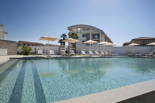 a swimming pool with chairs and umbrellas on a building at Modica Beach Resort in Marina di Modica
