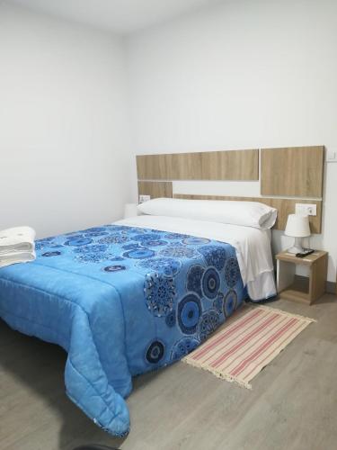 a bedroom with a bed with a blue comforter at Pension Diana in O Pedrouzo