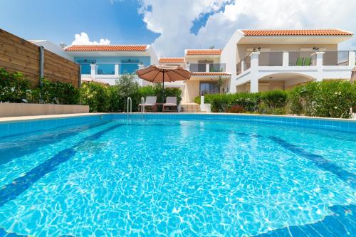 a swimming pool in front of a house at Kolymbia Village in Kolymbia