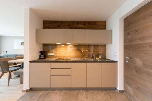 a kitchen with white cabinets and a wooden wall at Moar am Ort in Schenna