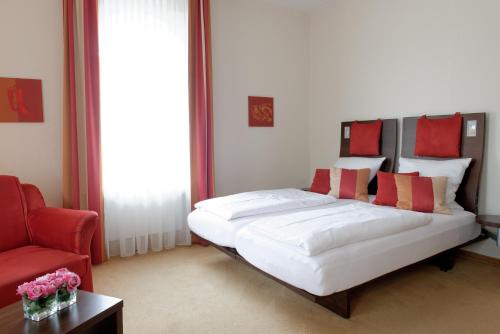 ein Schlafzimmer mit einem großen weißen Bett mit roten Kissen in der Unterkunft Maris Hotel in Steinhude