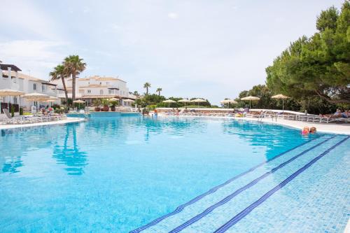 a large swimming pool with blue water in a resort at Grupotel Aldea Cala'n Bosch in Cala'n Bosch