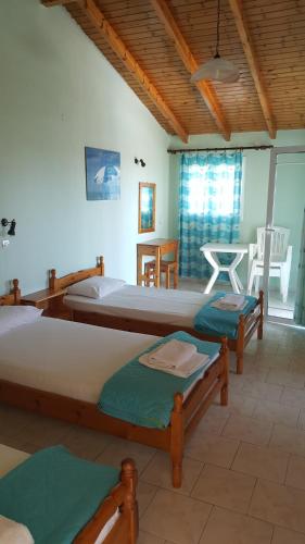 1 Schlafzimmer mit 3 Betten, einem Tisch und Stühlen in der Unterkunft Apollo in Kavos