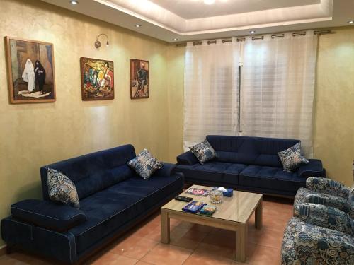 a living room with two blue couches and a table at Résidence Bab Sebta in Fnidek