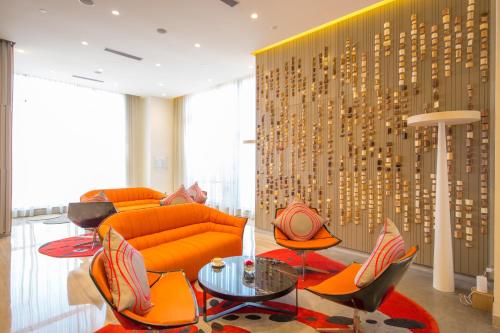 a living room with an orange couch and chairs at Novotel Chennai OMR in Chennai