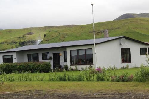 a white house with a hill in the background at Fosstún Guesthouse in Skogar
