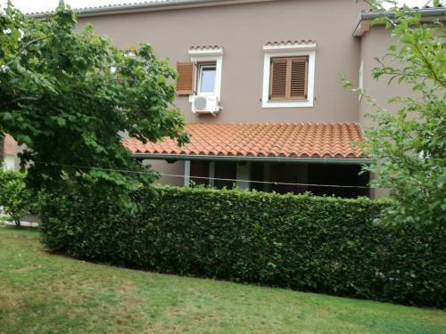 a house with a hedge in front of a building at Apartman Lovor in Medulin