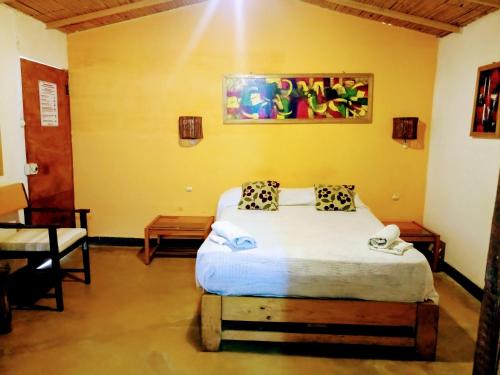 a bedroom with a bed in a yellow room at Guacamayo Rooms & Bungalows in Máncora