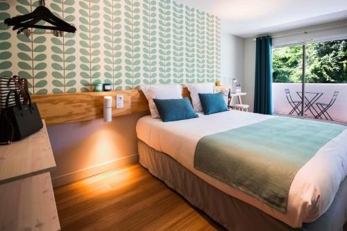 a bedroom with a large bed with blue pillows at T Boutique Hotel in Arcachon