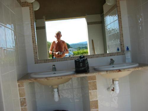 a man standing in front of a mirror in a bathroom at La Grange de Campaulise - Camping à la ferme - Hébergements - Mont Ventoux in Mazan
