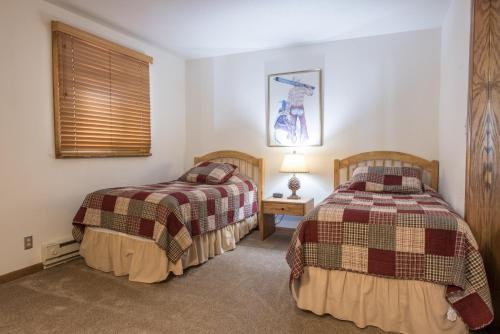 a bedroom with two beds and a lamp on a table at The Plaza Condominiums by Crested Butte Mountain Resort in Mount Crested Butte
