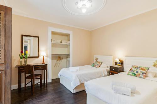 カマラ・デ・ロボスにあるCasa da Aldeia by An Island Apartのベッド2台、デスク、椅子が備わるホテルルームです。