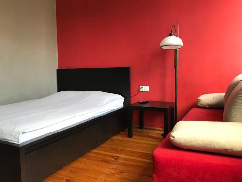 a bedroom with a bed and a red wall at Promenada Studio in Gdańsk