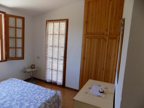 a bedroom with a bed and a door and a table at Casa Vacanze Gardenia in Solanas