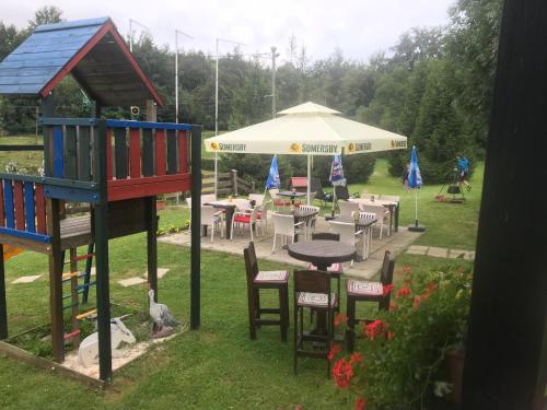 a playground with a table and chairs and an umbrella at Pansion Danica in Rastovača