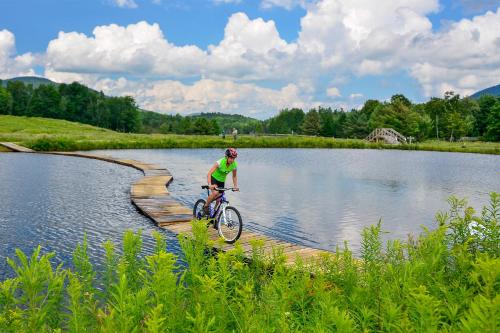 a person riding a bike on a bridge over a lake at The Glen House in Gorham
