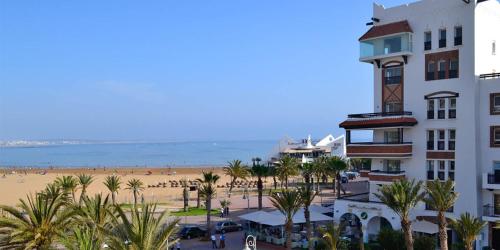 a building next to a beach with palm trees at Appartement Luxe Marina Agadir in Agadir