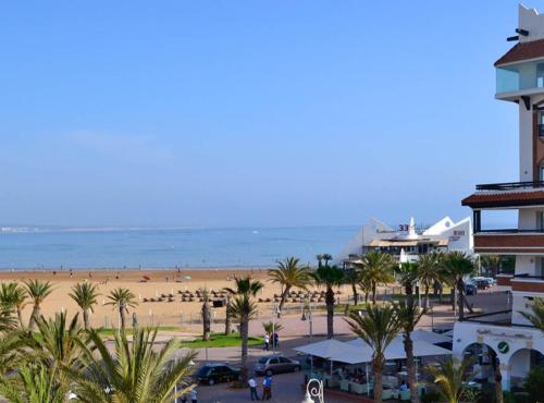 a view of a beach with palm trees and a building at Appartement Luxe Marina Agadir in Agadir