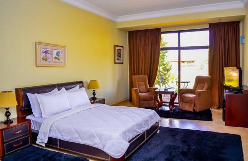 um quarto com uma cama grande e 2 cadeiras em Hôtel Jnane Ain Asserdoune em Oulad Yaïch