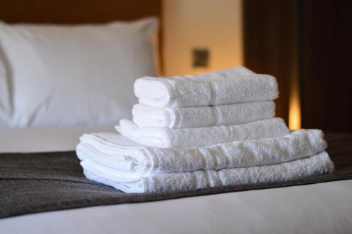 una pila di asciugamani poggiata sopra un letto di Q8 Boutique Hotel a Portsmouth
