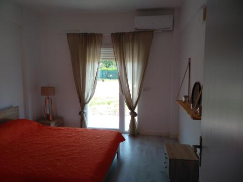 a bedroom with a red bed and a large window at Villa Katia in Vourvourou
