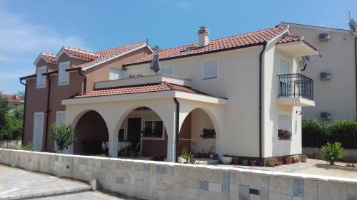 Cette grande maison blanche est dotée d'un mur en pierre. dans l'établissement Apartment Ninić, à Srima