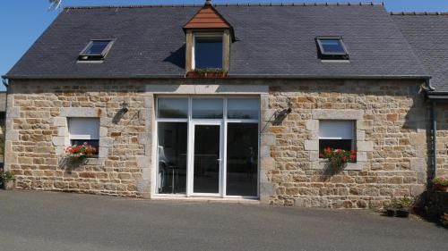 a brick building with two windows and a door at La ferme Guibel in Plouzélambre