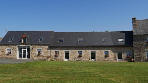 a large stone building with a grass field in front at La ferme Guibel in Plouzélambre