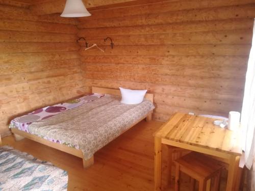 Kleines Zimmer mit einem Bett und einem Tisch in der Unterkunft Kempings Ozianna in Naujene
