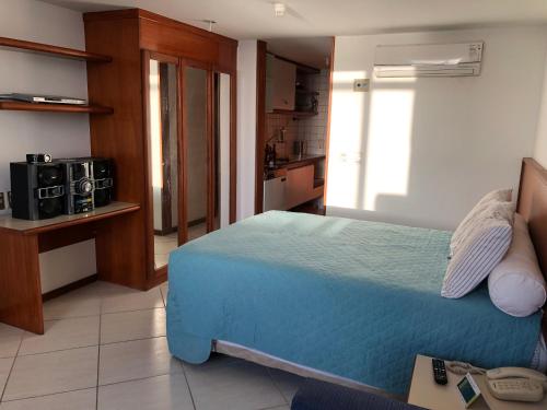 una camera con letto blu e una cucina di Flat Privativo Sol Victoria Marina a Salvador