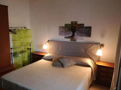 ein Schlafzimmer mit einem großen weißen Bett mit zwei Leuchten in der Unterkunft Appartamento Foglie in Bovalino Marina