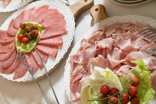 a table with two plates of food with meat and vegetables at TH Borca di Cadore - Park Hotel Des Dolomites in Borca di Cadore