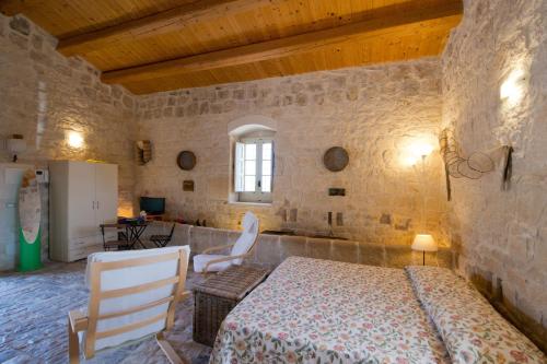 a bedroom with a bed and chairs in a stone wall at Antica Masseria Adamo in Sampieri