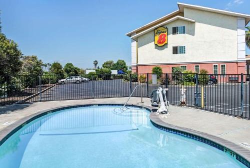 a swimming pool in front of a building with a fence at Super 8 by Wyndham Sacramento/Florin Rd in Sacramento