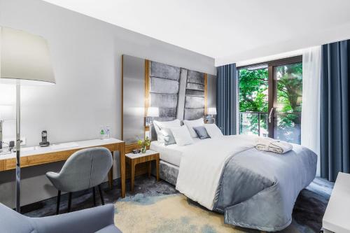 a bedroom with a bed and a desk and a sink at Hotel Testa in Sopot