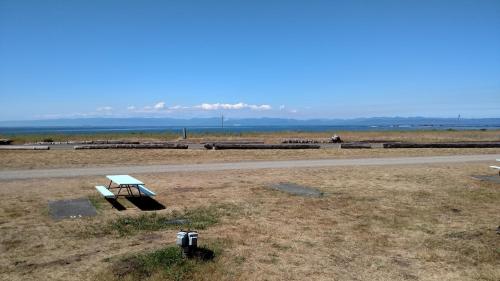 a picnic table in a field next to a road at Crescent Beach and RV Park in Port Angeles