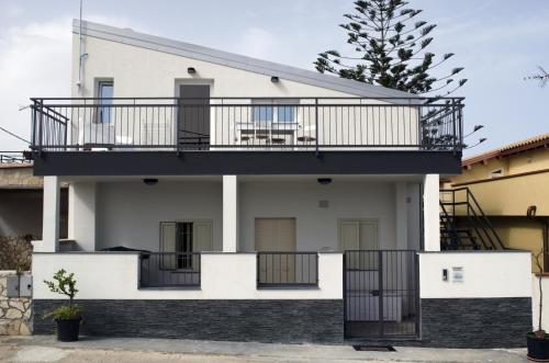 a white house with a balcony on top at Ansise apartments in Noto Marina
