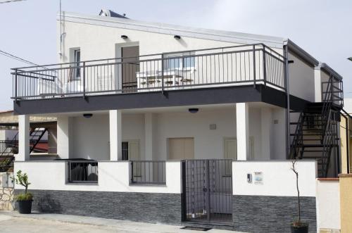 a house with a balcony and a staircase at Ansise apartments in Noto Marina