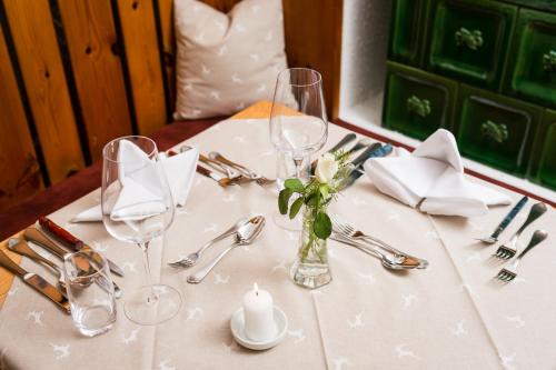 a table with glasses and a vase of flowers on it at Gasthof Kronreith in Maria Alm am Steinernen Meer