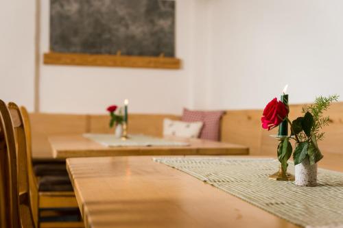 a table with a rose in a vase on it at Gasthof Kronreith in Maria Alm am Steinernen Meer