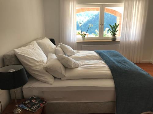 a bed with white pillows and a window in a room at Schwarzwald Lodge Oppenau in Oppenau