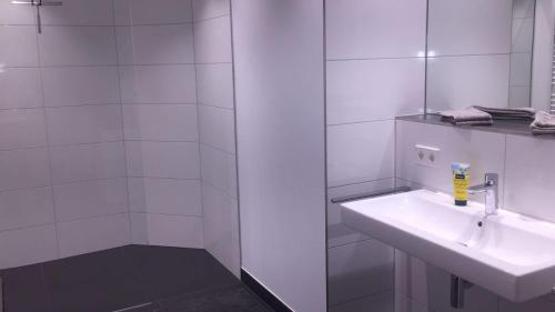 a white bathroom with a sink and a mirror at Schwarzwald Lodge Oppenau in Oppenau