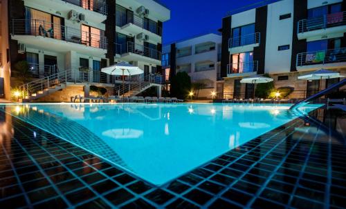 an empty swimming pool in front of buildings at night at New Line Village Apartments in Sunny Beach